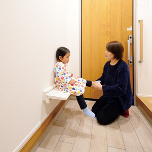 遊びに来る祖母のために玄関に設けた折りたたみのいす。<br>
子どもに靴を履かせるのにも便利