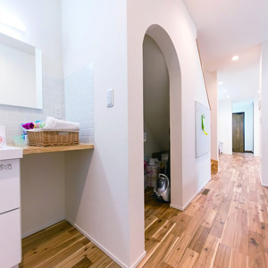 玄関から洗面、トイレ、浴室まで一直線に続く「ただいま動線」が子どもの自主性を促す。階段下の壁をアーチ状にくりぬいて収納に