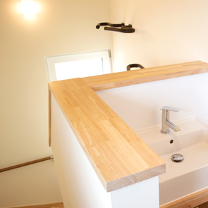 階段を上がってすぐに使いやすい洗面台。階段にはこだわりのサーフィンボードの収納場所。